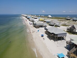 A beachside property with multiple wooden structures, some with balconies, overlooking a sandy beach and the ocean. - LA Lady | Book for spring break trip now for the best prices! (Dauphin Island)