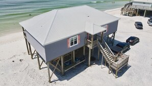 Une maison de plage avec un balcon, un escalier et une vue sur l’océan.