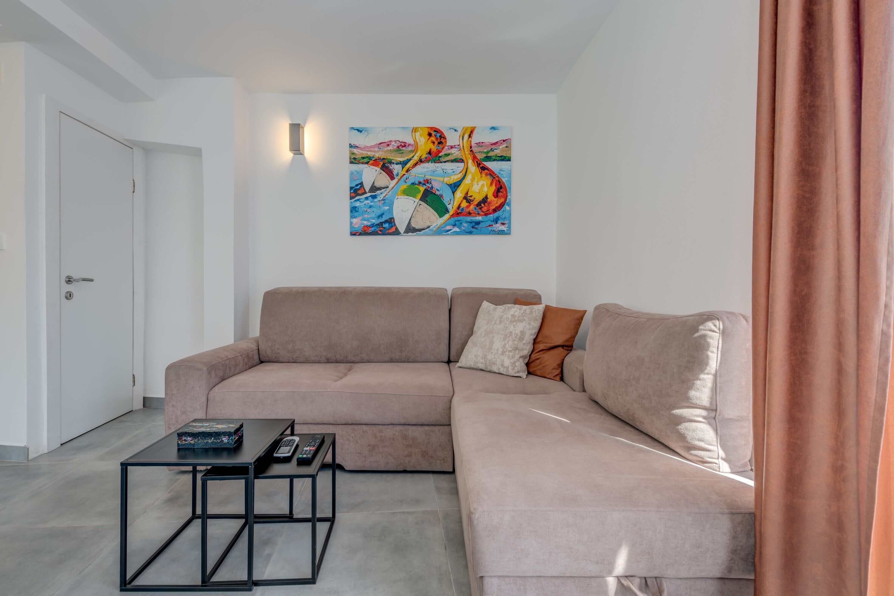 Un soggiorno moderno con un divano color beige, un tavolino da caffè e un quadro appeso al muro.