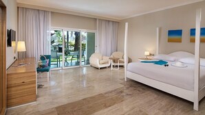 A hotel room with a large bed, a desk, a chair, and a view of the outdoors. - Cofresi Puerto Plata Dominican Republic  (Puerto Plata)