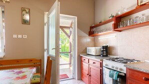 Una cocina con estufa, microondas y armarios. Hay una mesa de comedor con sillas y una ventana con vistas al exterior.