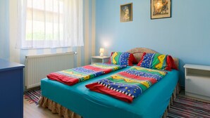 Un dormitorio con cama, mesita de noche, lámpara y dos cuadros en la pared.