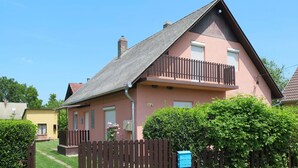 Una casa de dos pisos con techo inclinado, un balcón y una cerca de madera.