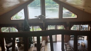 A room with a high ceiling and large windows overlooking a body of water.