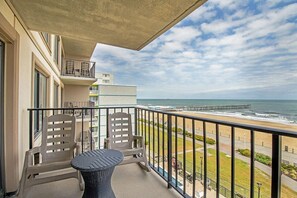 A balcony with a view of the beach, a table, and two chairs. - The Colony - Oceanfront 2BR/2BA - Great Views! (Virginia Beach)