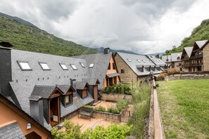 Ein Wohngebiet mit mehreren Häusern, die Schrägdächer und Dachfenster haben, umgeben von üppiger Vegetation und Hügeln im Hintergrund.