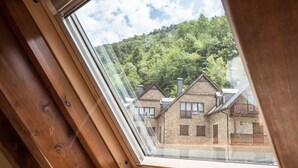 A view from a skylight of a traditional stone building with multiple windows and balconies, surrounded by lush greenery. - Casa Artiga de Lin (Bòrdes (Es))