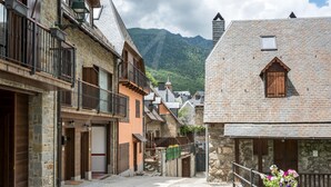A narrow street with stone buildings, balconies, and a mountain backdrop. - Casa Artiga de Lin (Bòrdes (Es))