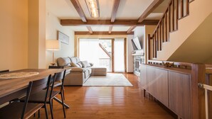 A modern kitchen with wooden cabinets, a dining table with chairs, and a staircase leading to an upper level. - Casa Artiga de Lin (Bòrdes (Es))