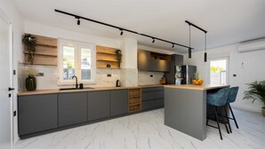Una cocina moderna con una isla central, armarios oscuros y un salpicadero de mármol.