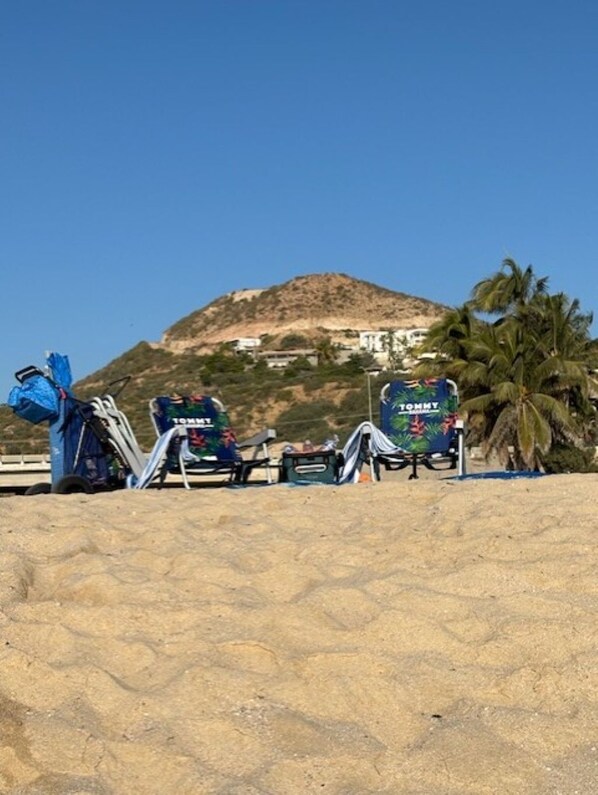 A beach with a mountain in the background, a palm tree, and a Tommy Hilfiger sign. - Private 3 bed 3 bath home with it's own pool and amazing ocean views. (San José del Cabo)
