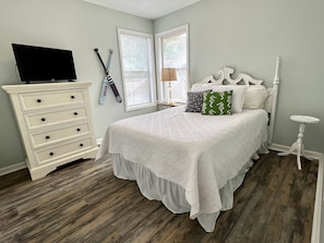 A bedroom with a bed, dresser, and a television.