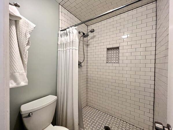 A bathroom with a toilet, a shower with a glass door, and a tiled floor. - Bright, newly updated 3 BR 2 BA condo - Walk to Pier and Village! (St. Simons Island)