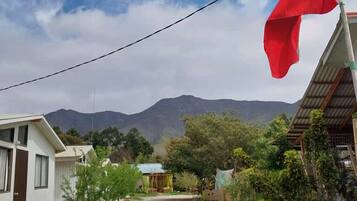 A residential area with a flagpole, a small building, and a mountain in the background.