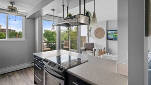Una cocina moderna con una isla grande, horno integrado e iluminación colgante.