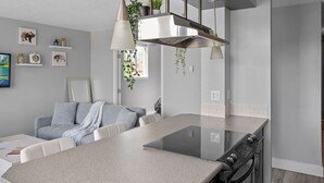 Una cocina moderna con una isla central, luces colgantes y un horno empotrado.