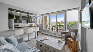 A modern apartment with a kitchen, dining area, and living room. It features large windows, a balcony, and a city view.