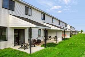 A row of single-story houses with attached porches, each with a patio table and chairs.