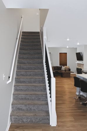 Eine Treppe führt zu einem Wohnbereich mit einer Couch und einem Flachbildfernseher.