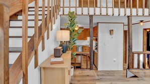 A wooden staircase with a modern interior design, a kitchen area with wooden cabinets, and a dining space with a table and chairs.