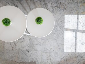 Two white round tables with green centerpieces on a marble floor.