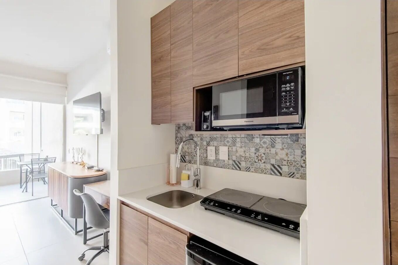 Una cocina moderna con microondas integrado, estufa y pileta.