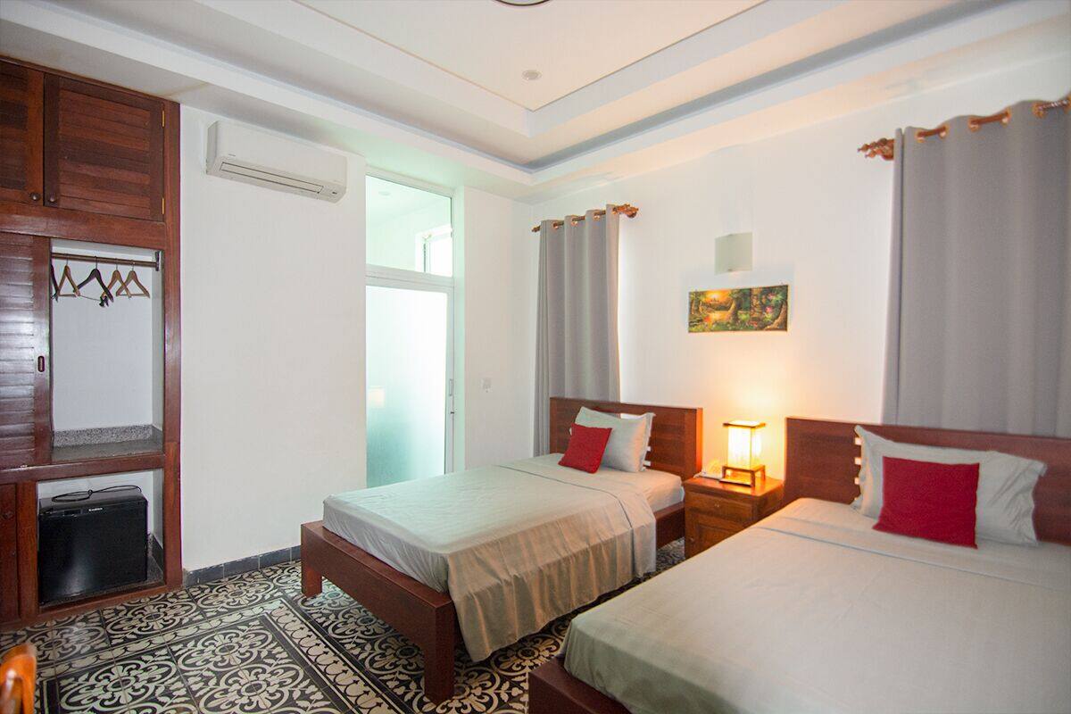 Une chambre d’hôtel avec deux lits, une armoire, un porte-manteau et un tableau au mur.