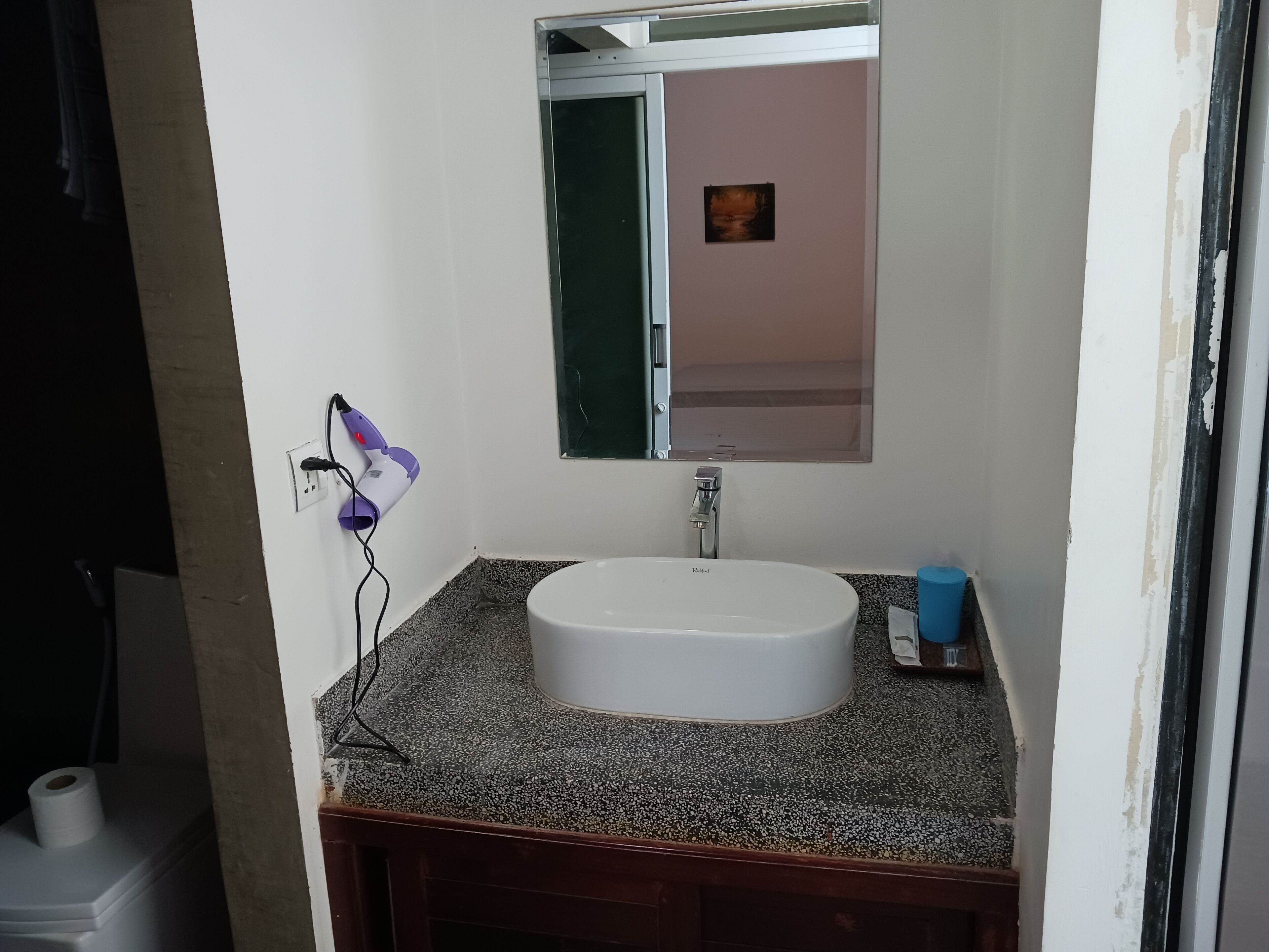 Ein Badezimmer mit einem weißen Waschbecken, einem Spiegel und einem Föhn an der Wand.