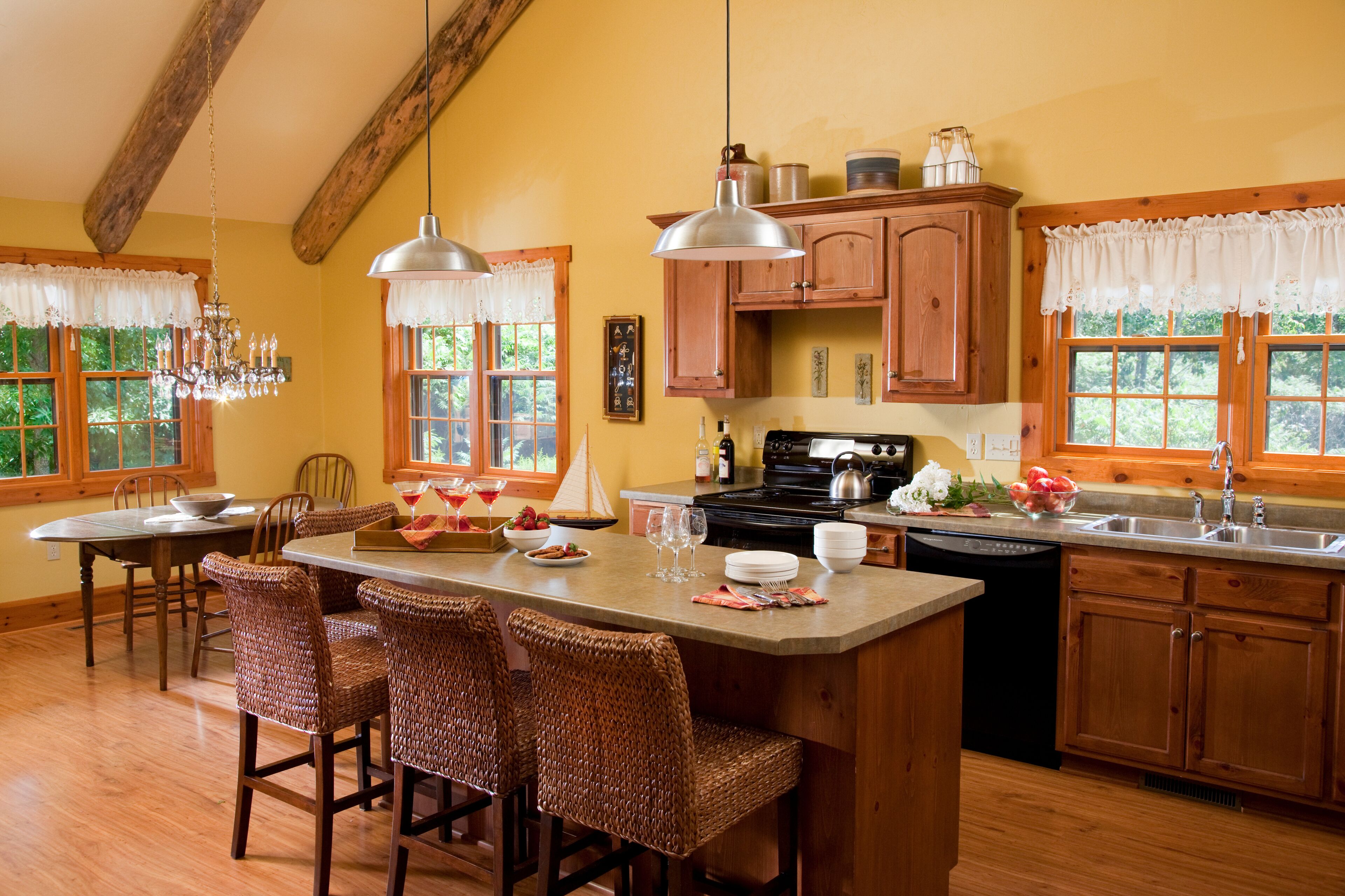 A kitchen with wooden cabinets, a central island with bar stools, a stove, and a dishwasher.