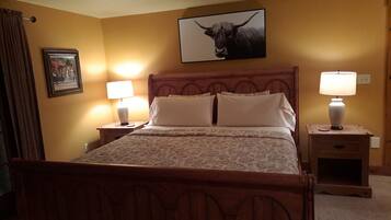 Une chambre à coucher avec un lit en bois, deux tables de chevet avec des lampes, un ventilateur de plafond et un tableau encadré au mur.