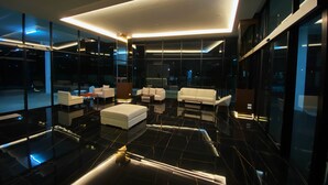 A modern interior with a central white sofa, a coffee table, and a glass partition. - GEEN Hotel Chonburi (Chonburi)