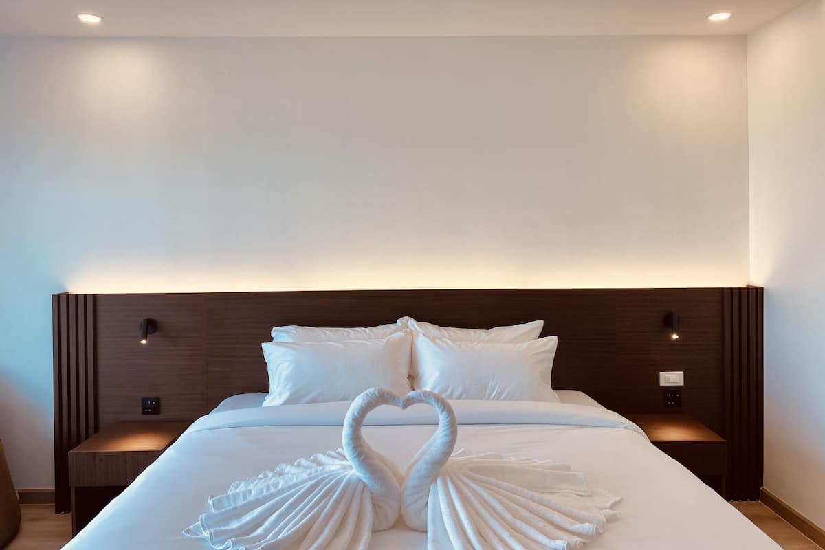 A hotel room with a neatly made bed, two bedside tables, and a wall-mounted light fixture.