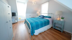 Ein Schlafzimmer mit Bett, Nachttisch, Lampe und Kleiderschrank.