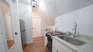 Eine kleine Küche mit Herd, Backofen, Spüle und Kühlschrank.