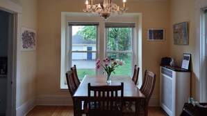 A dining room with a wooden table, chairs, a chandelier, and a vase with flowers. - 1910 Family Home near Lake Winnebago, available for EAA (Oshkosh)