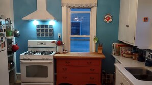 A kitchen with a gas stove, oven, and a red wooden cabinet. - 1910 Family Home near Lake Winnebago, available for EAA (Oshkosh)