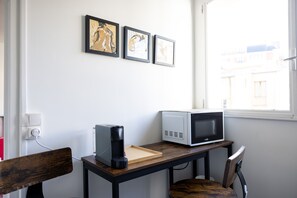 Cozy retreat with a desk, microwave, and coffee maker, plus a window offering a view of the outside.