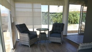Un patio couvert aménagé avec des meubles en osier, comprenant deux chaises et une petite table.