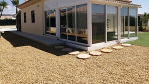 Une maison moderne dotée de grandes fenêtres en verre, d’un toit en tuiles et d’une allée gravillonnée.