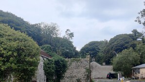 A rural setting with a stone wall, a small building with a sloped roof, and a gravel driveway. - Lovely 4-bed property in Mullaghbawn (NEWRY)
