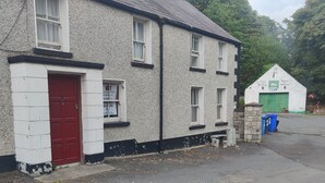 A two-story stone building with a red door and multiple windows. - Lovely 4-bed property in Mullaghbawn (NEWRY)