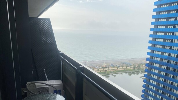 Un balcón con vista al mar y un edificio al otro lado del agua.