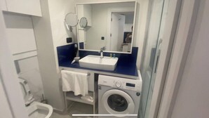 Un baño pequeño con lavamanos, espejo y lavadora.