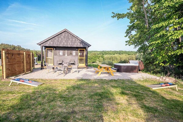 Une cabane en bois avec un garage, un espace salon extérieur et un jacuzzi.
