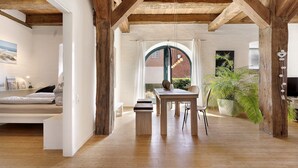 Amplia habitación con techo de madera, una cama, una mesa de comedor y un ventanal grande.