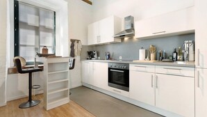 Una cocina moderna con armarios blancos, horno empotrado y un taburete de bar.