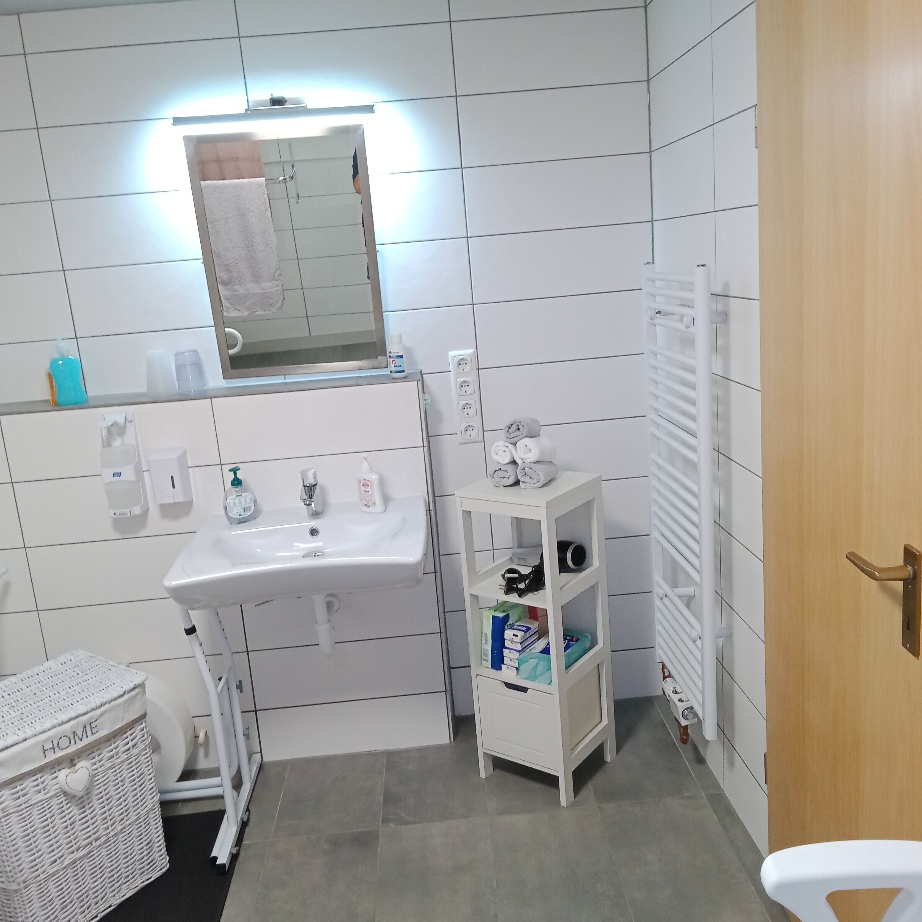 A bathroom with a sink, mirror, towel rack, and a small shelf with toiletries.