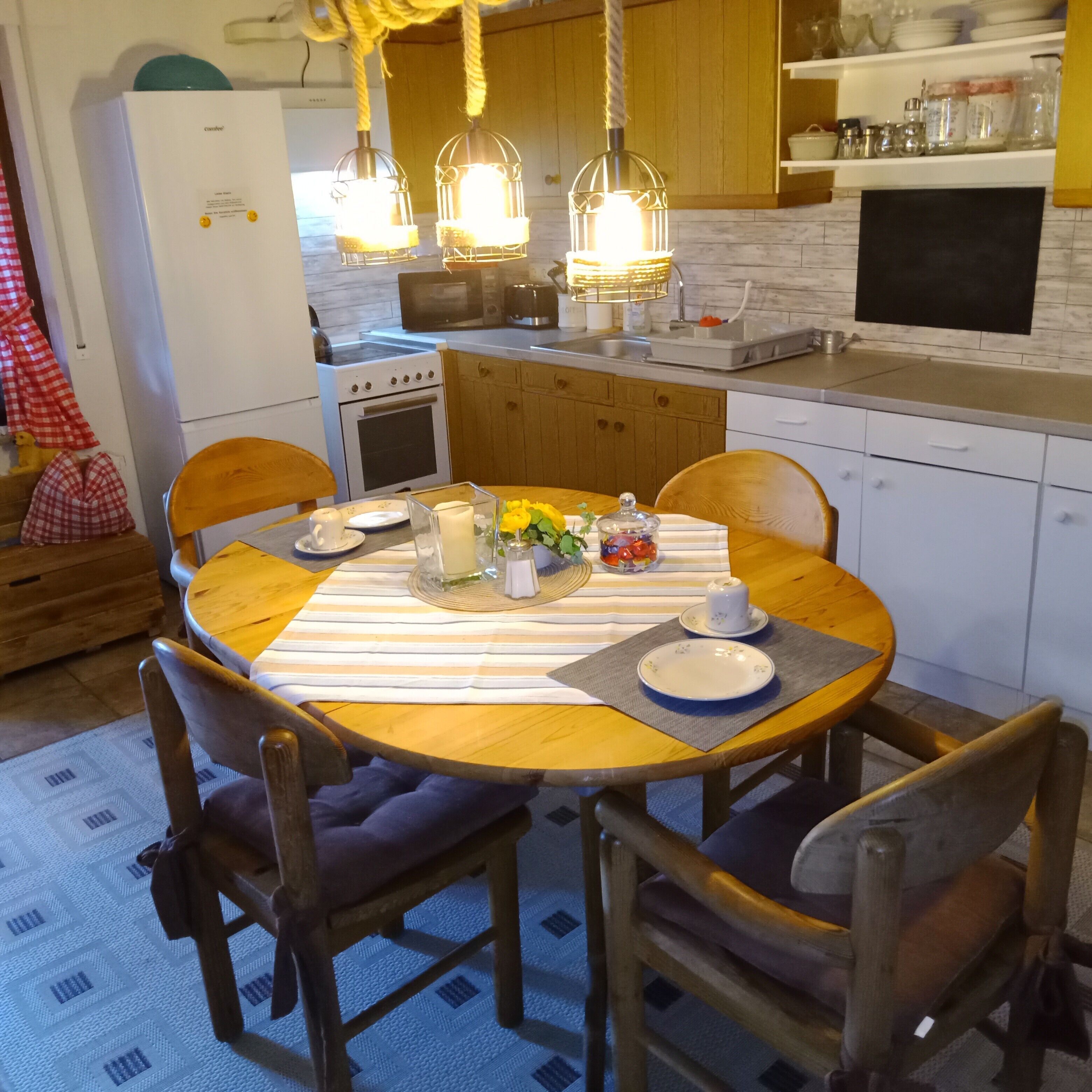 A kitchen with wooden cabinets, a stove, a microwave, and hanging pendant lights.