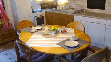A kitchen with wooden cabinets, a stove, a microwave, and hanging pendant lights.