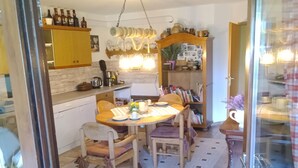 Una cocina con armarios de madera, una mesa de comedor con sillas y una lámpara colgante.